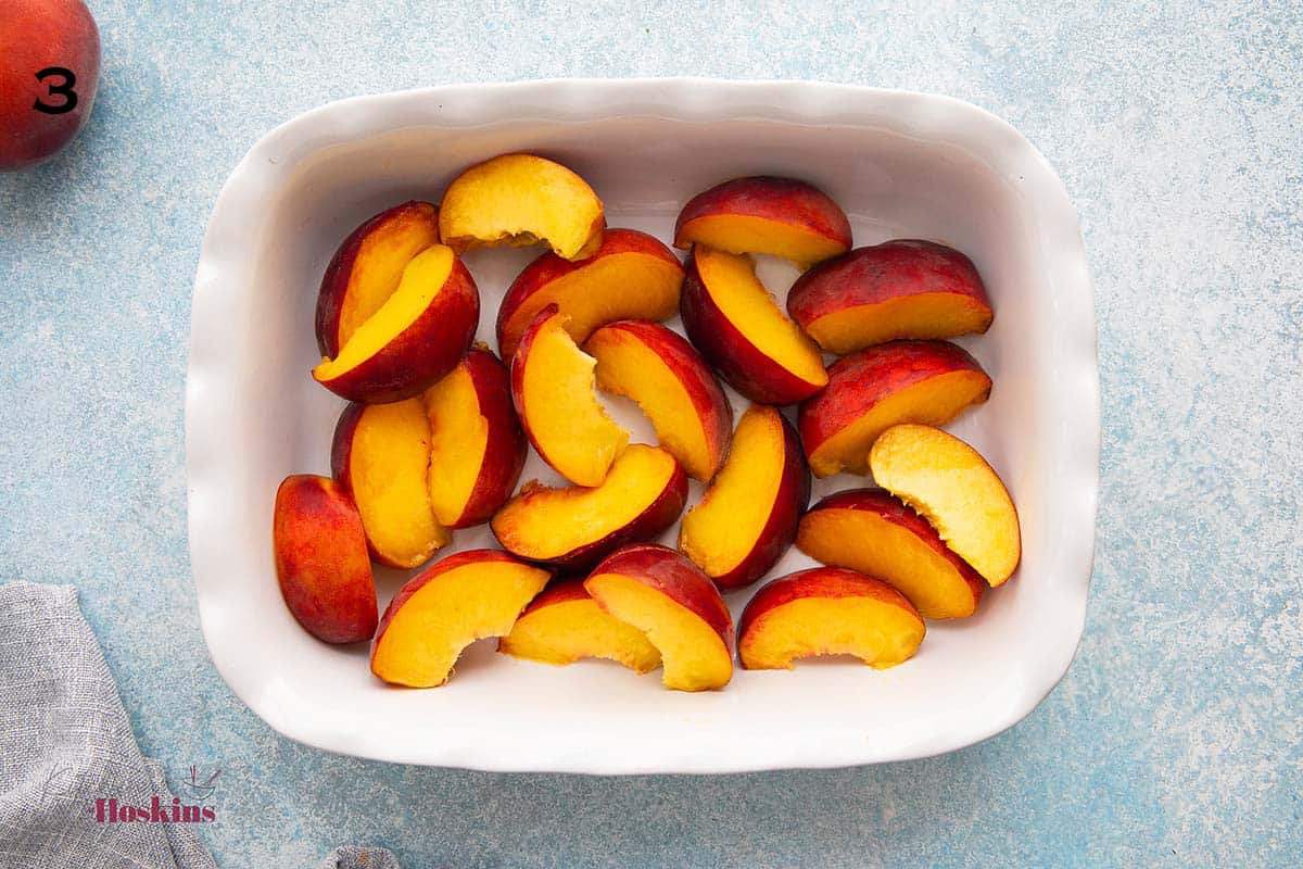 one white fluted baking dish with peach wedges.