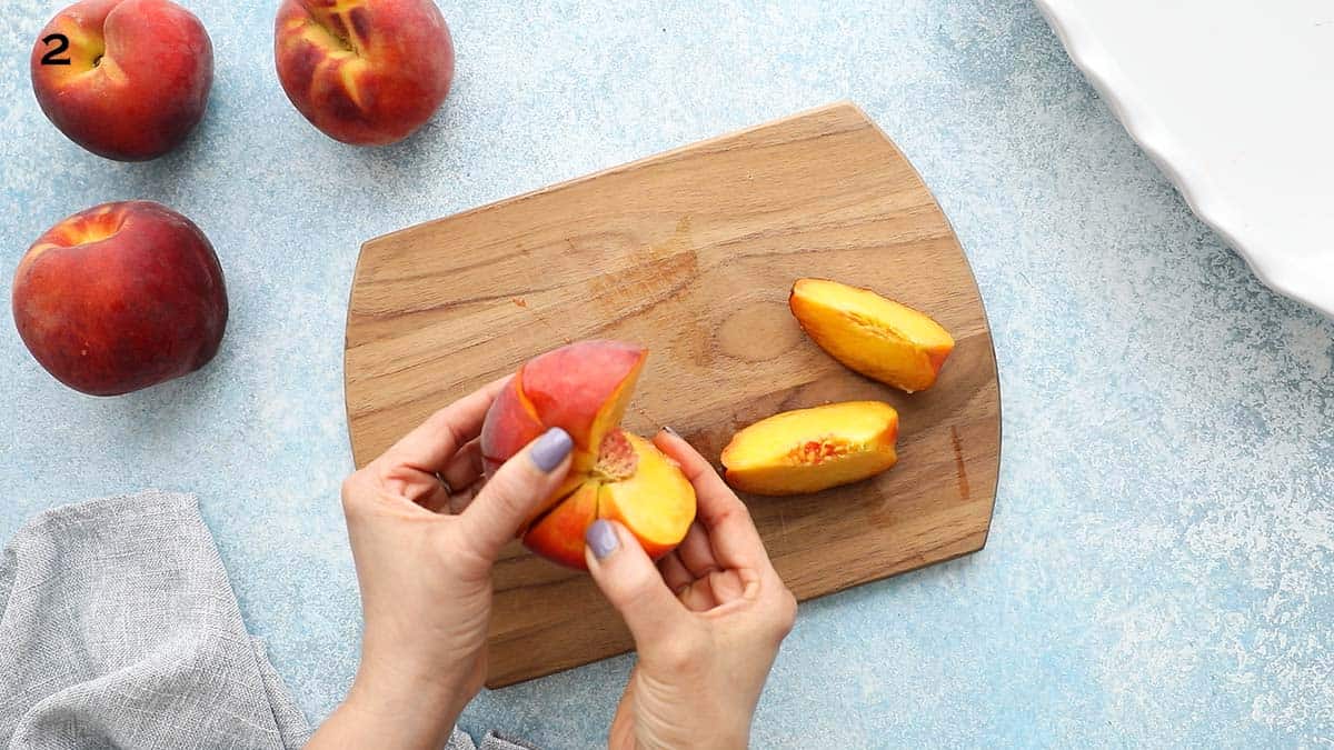 two hands removing wedges from a peach.