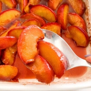 yellow baked peaches in a white dish.