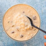 creamy white rice pudding in a glass bowl along with a black spoon.
