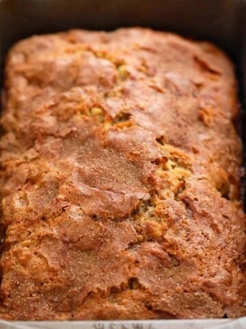 a metal loaf pan with baked apple bread.