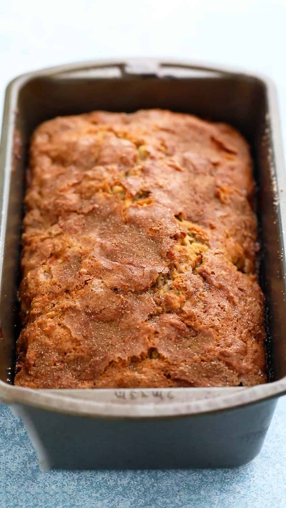 a metal loaf pan with baked apple bread.