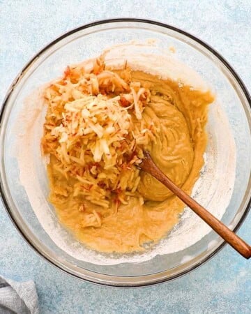 grated apples along with muffin batter in a glass bowl.