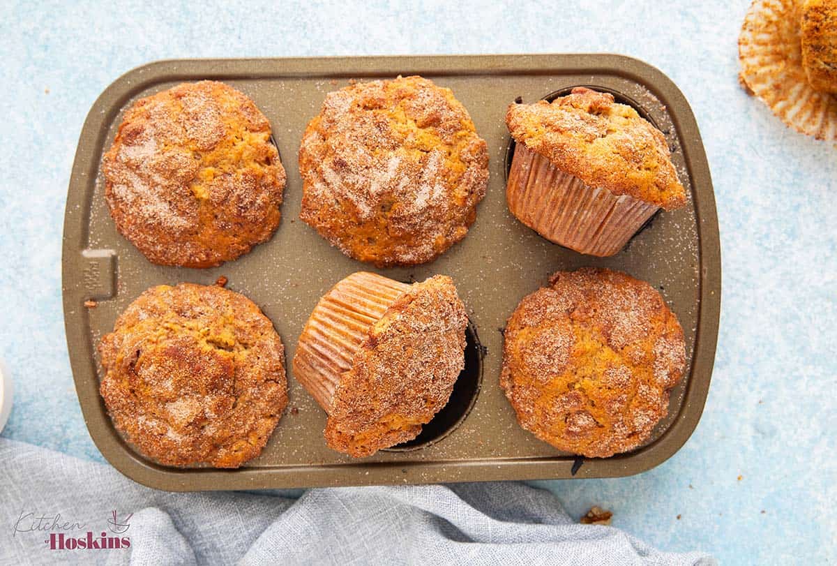 a 6-cup metal muffin pan with baked apple muffins.