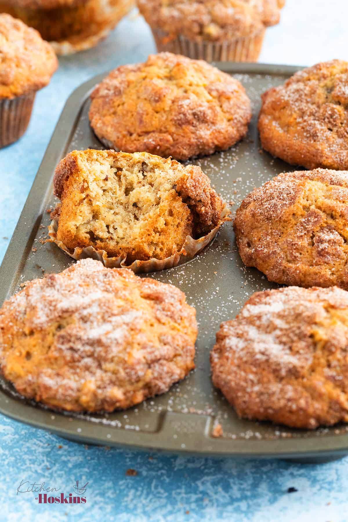 a 6-cup metal muffin pan with baked apple muffins.