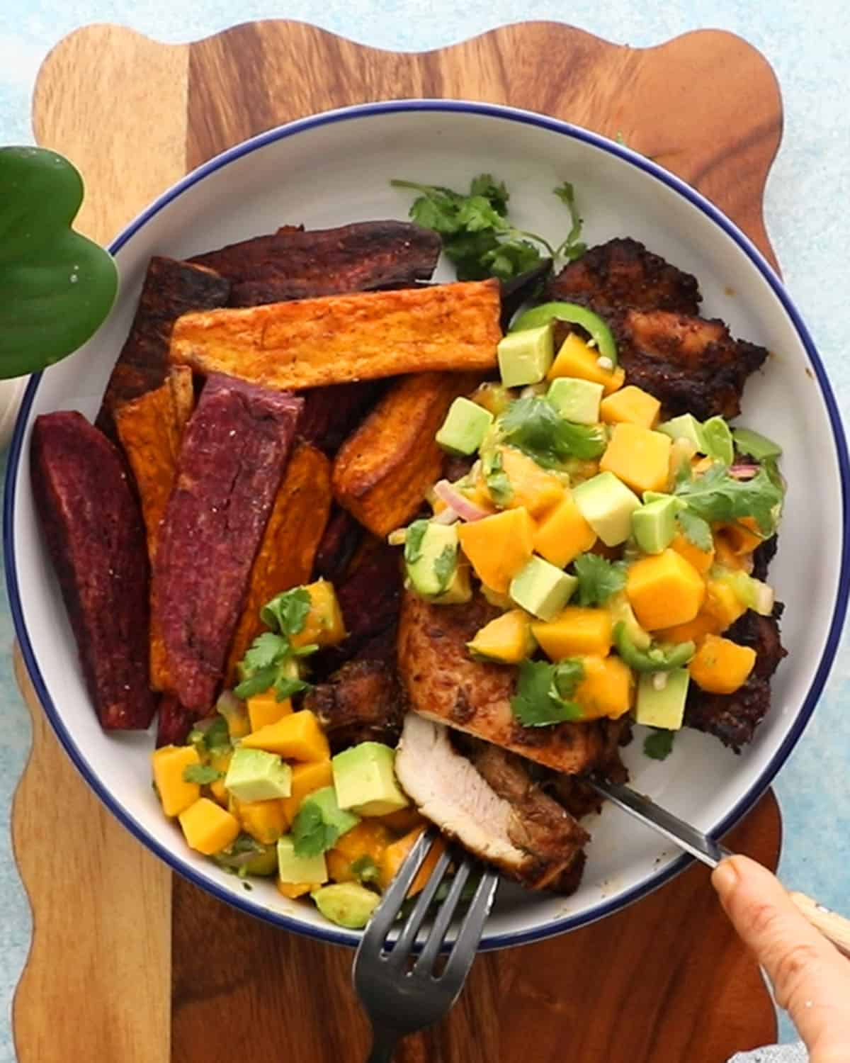 blackened chicken topped with yellow and green salsa in a white bowl.
