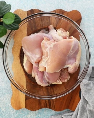 raw pink chicken in a glass bowl.