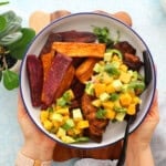 blackened chicken with yellow and green salsa in a white bowl.