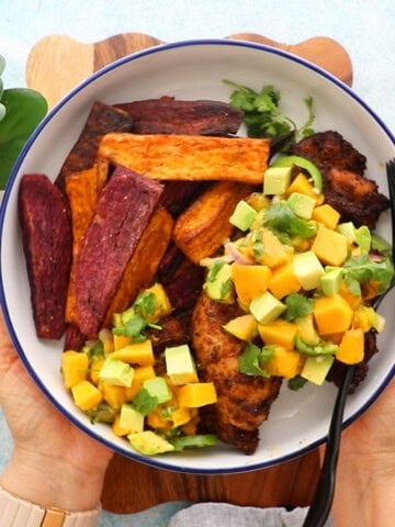 blackened chicken with yellow and green salsa in a white bowl.