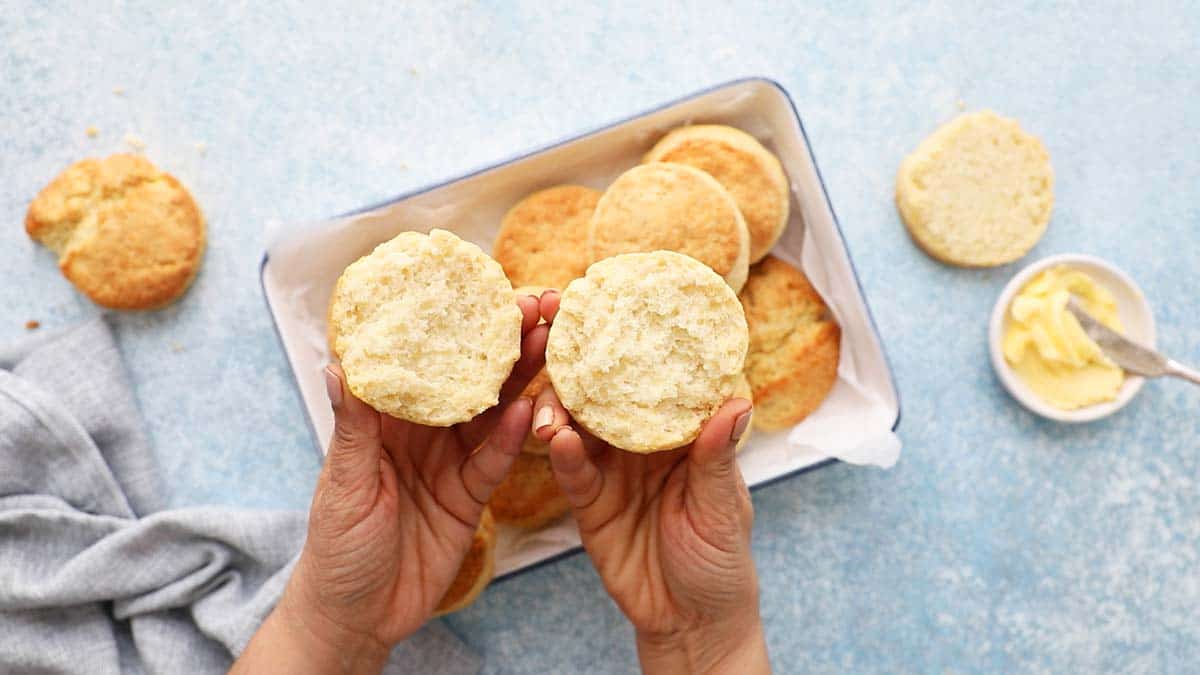 2 hands holding each half of a split open biscuit.