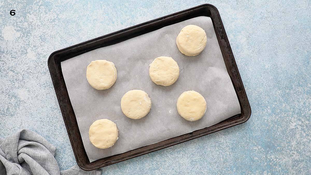 a black metal sheet pan with cut biscuit  dough.