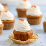 an open pumpkin cupcake topped with cream cheese frosting.