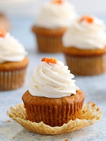 an open pumpkin cupcake topped with cream cheese frosting.
