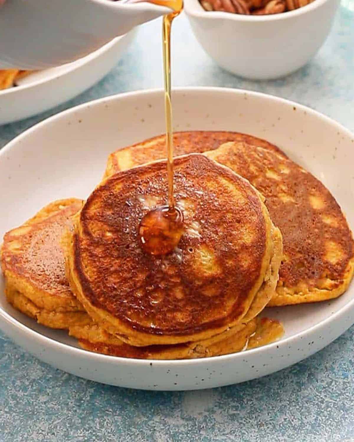 three pumpkin pancakes in a white plate.