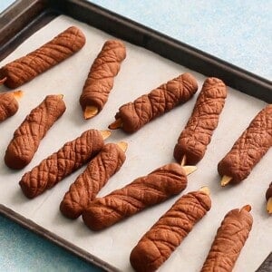 brown candle shaped cookies on a white paper lined baking sheet.