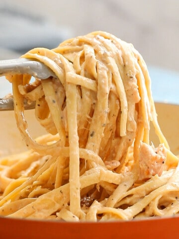 a hand serving cooked fettuccini using tongs.