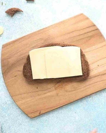 one brown grilled cheese sandwich on a wooden board.