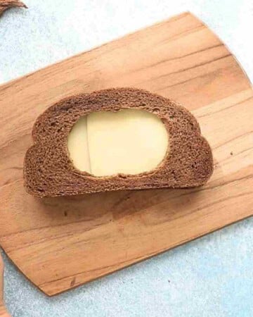 one brown grilled cheese sandwich on a wooden board.