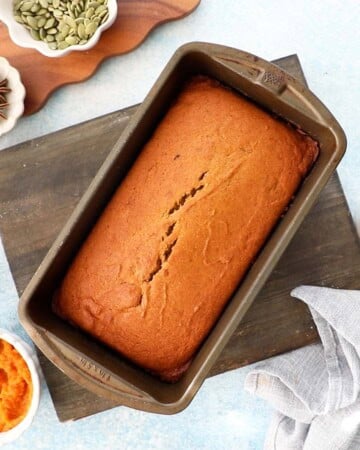 baked orange pumpkin cake in a metal loaf pan.