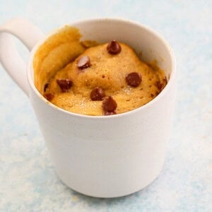 pumpkin cake topped with chocolate chips in a white mug.