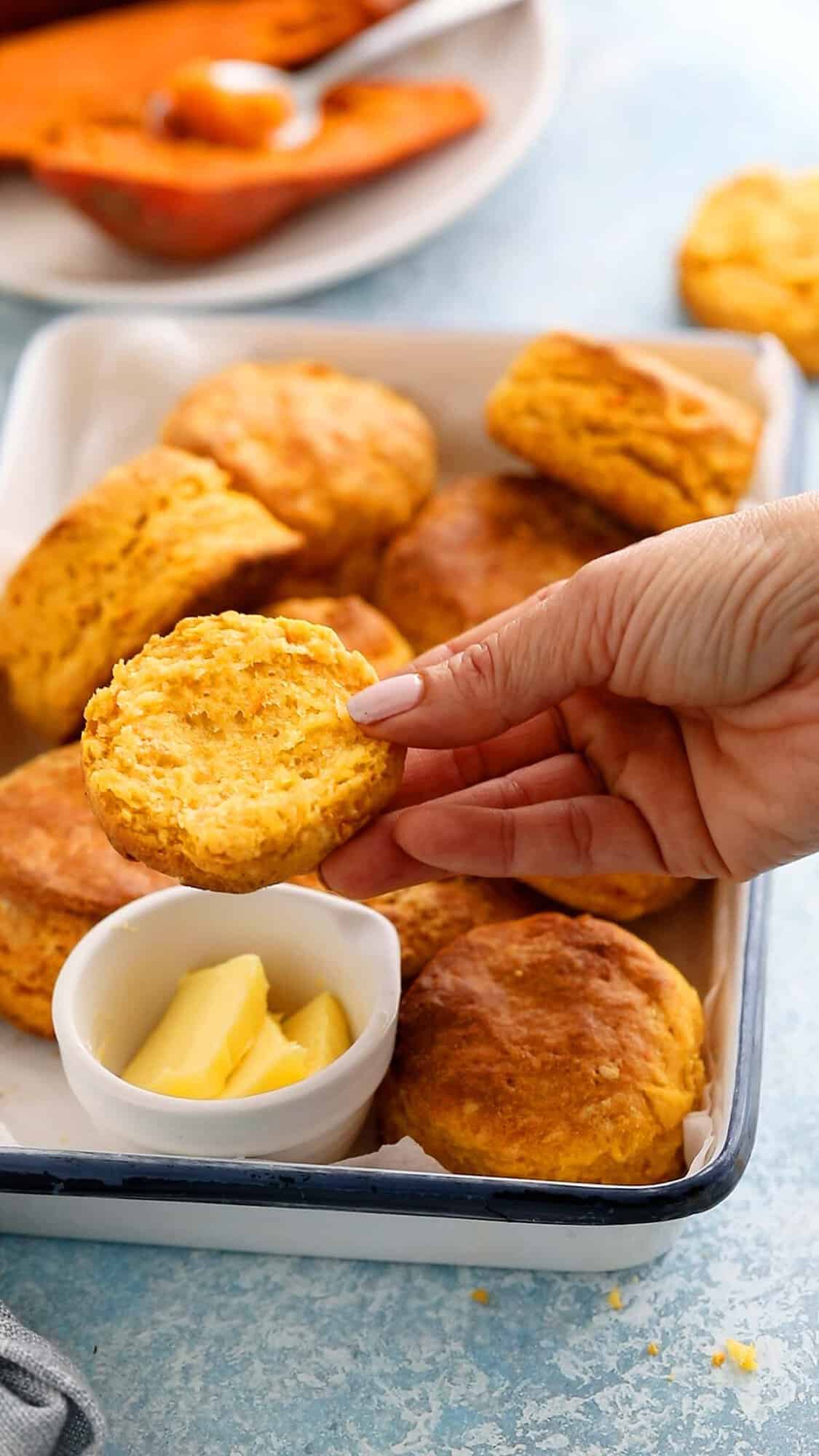 a hand holding a split open sweet potato biscuit.