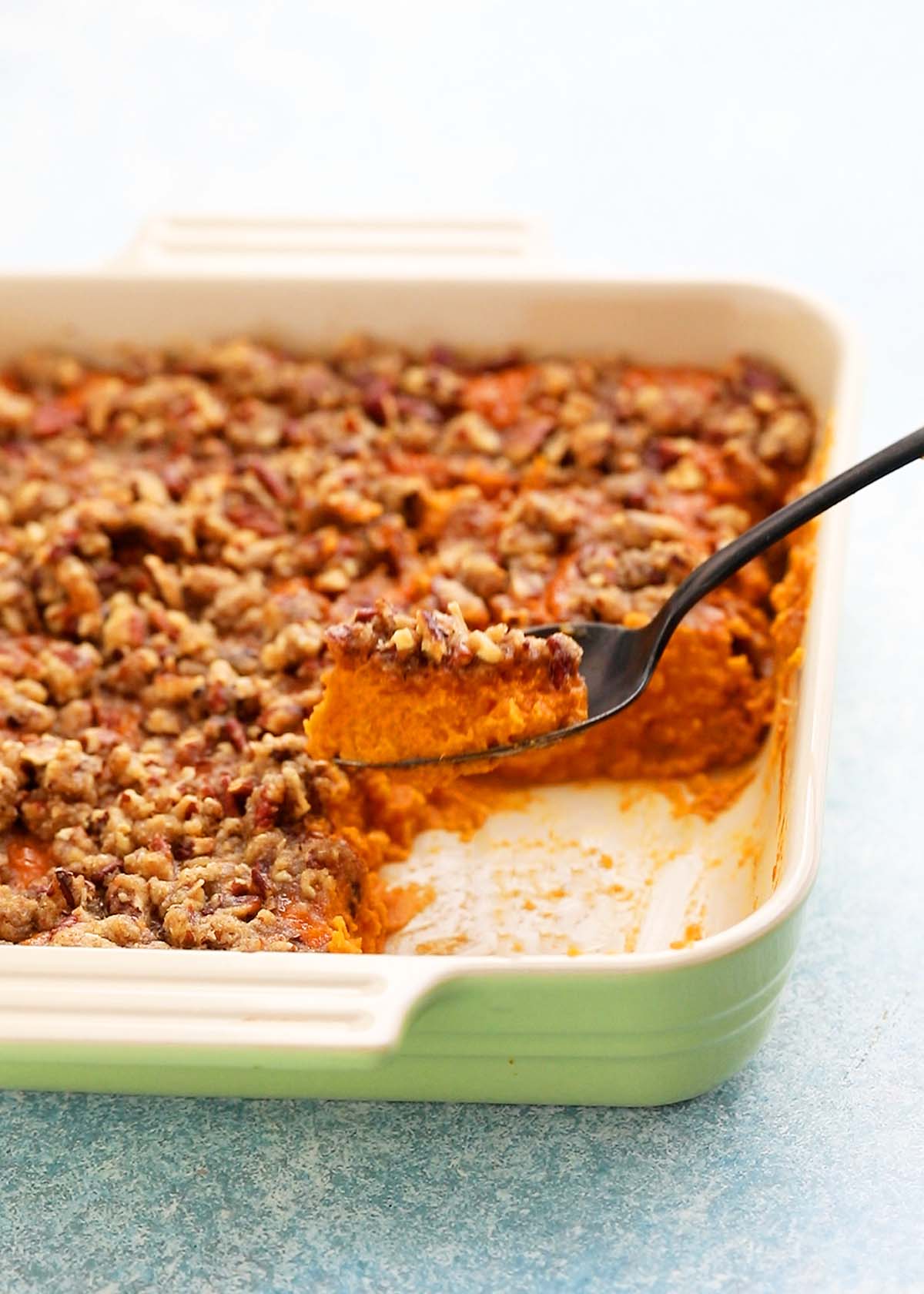 a spoonful of sweet potato souffle in a ceramic square dish.