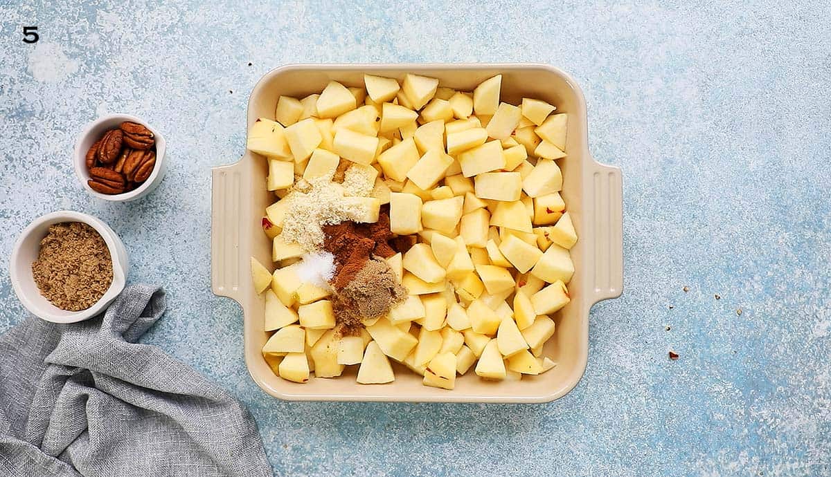 chopped apples along with cinnamon and brown sugar in a square baking dish.