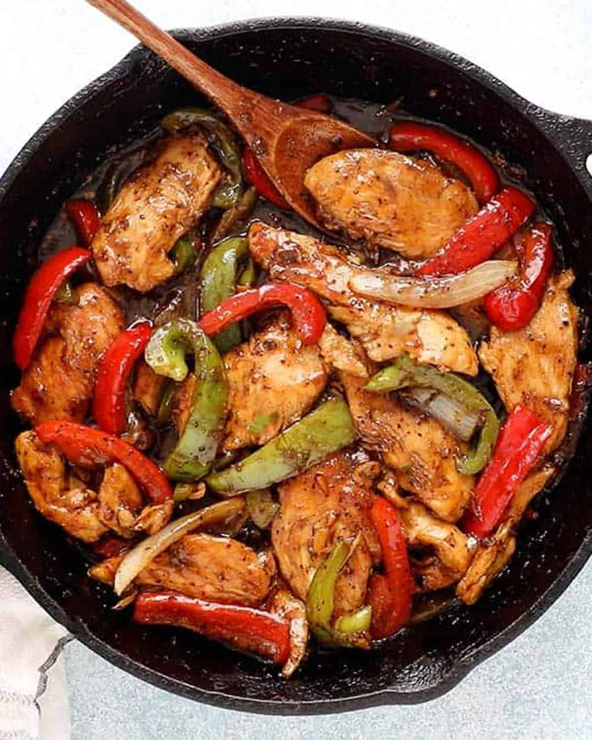 black pepper chicken stir fry in a black skillet.