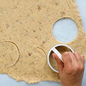 a hand cutting circles of cookie dough.
