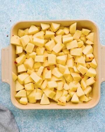 chopped apples placed in a square baking dish.