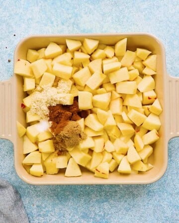 chopped apples topped with cinnamon, placed in a square baking dish.