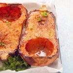 two cooked butternut squash halves placed in a white tray.