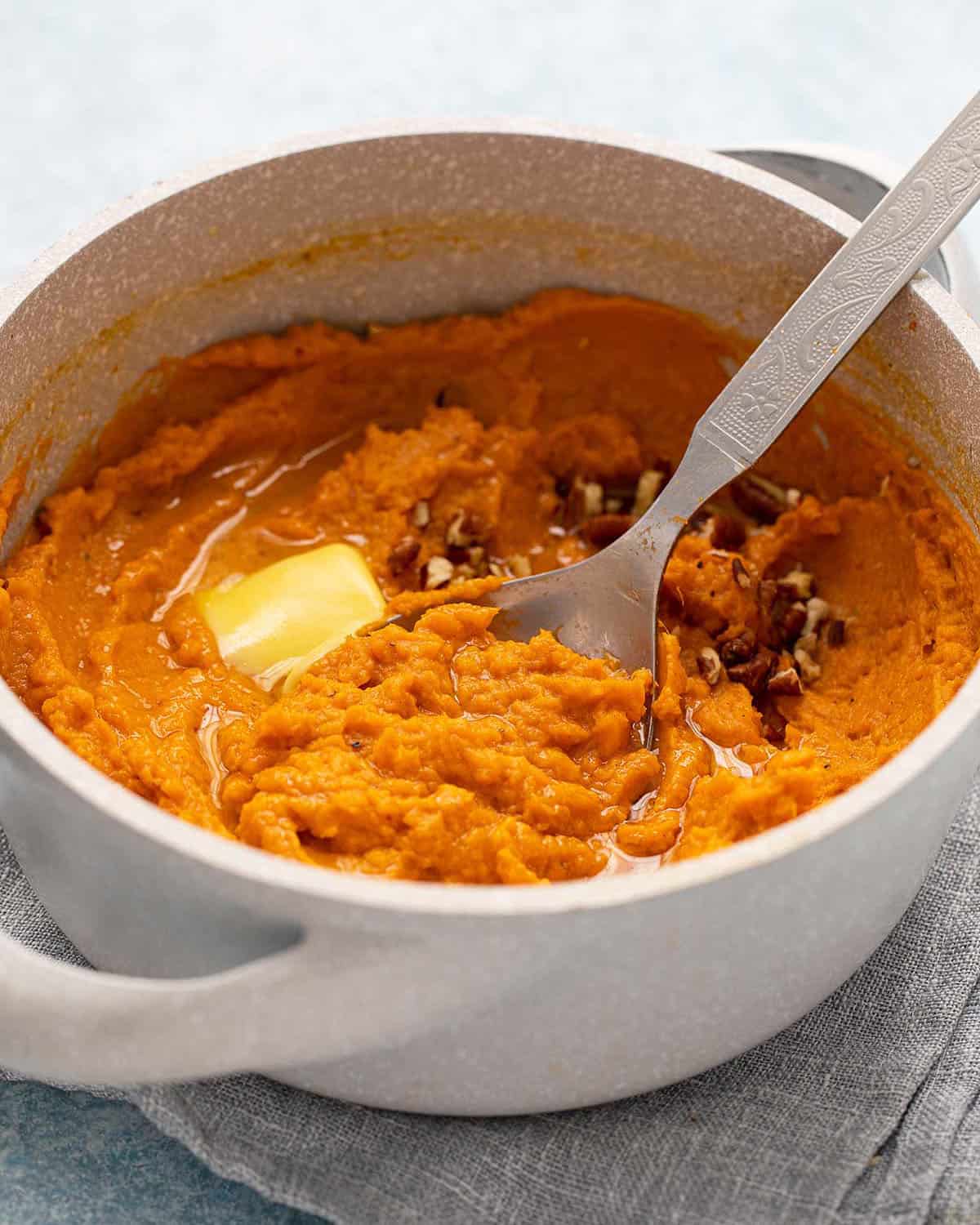 orange mashed sweet potatoes in a grey pot.