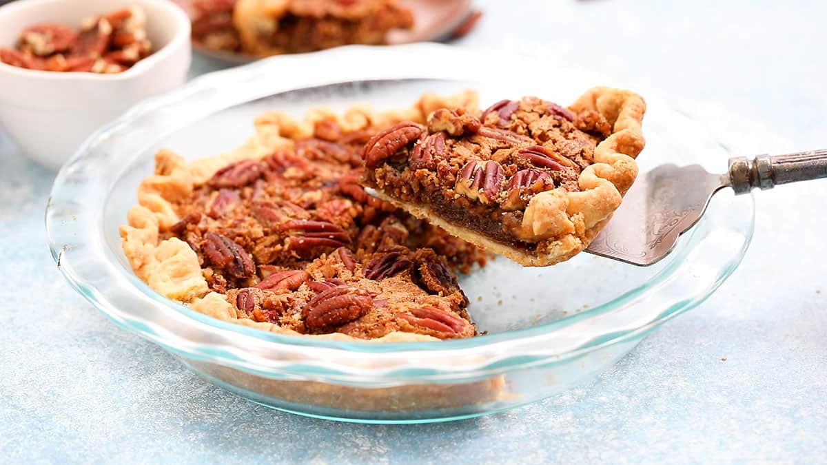 a slice of pecan pie being lifted from a pie plate.