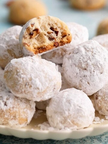 white pecan snowball cookies arranged om a white plate.