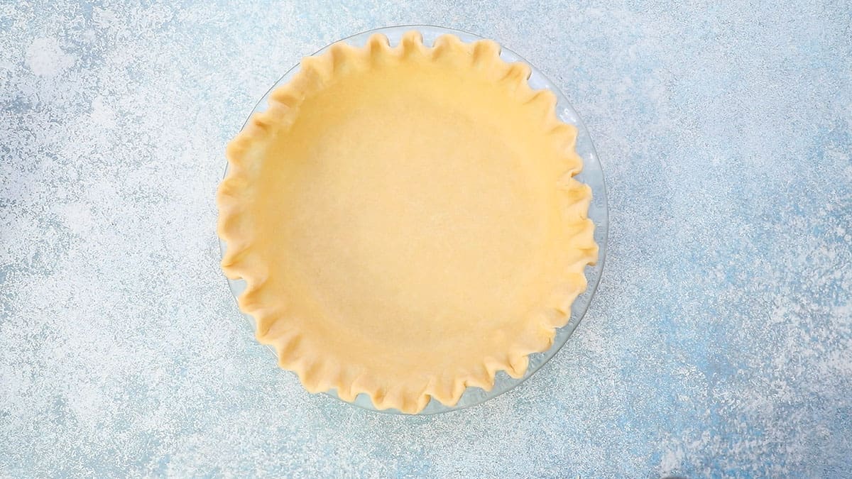 rolled and crimped pie crust on a glass pie plate.