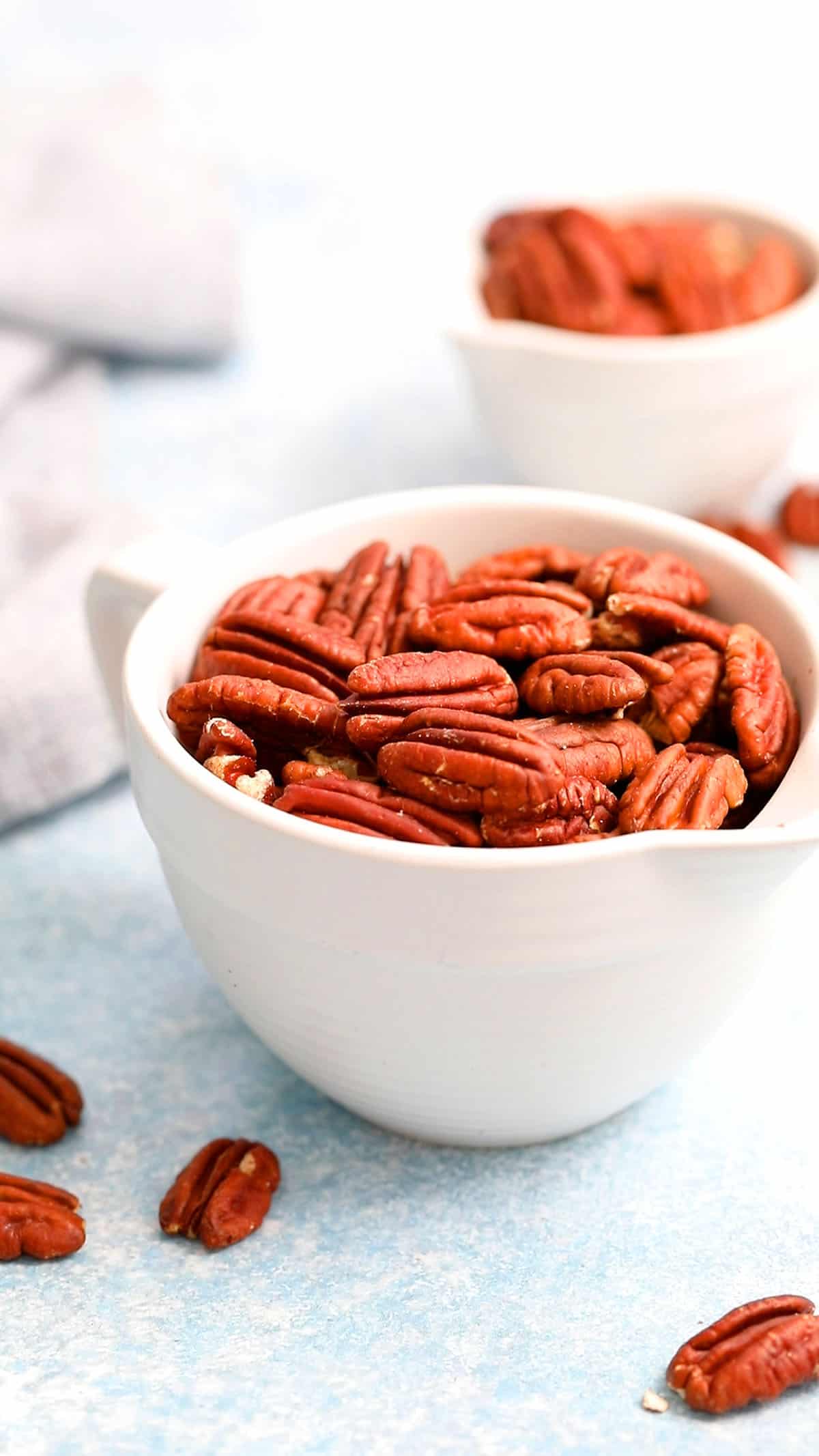 2 white bowls filled with toasted pecans.
