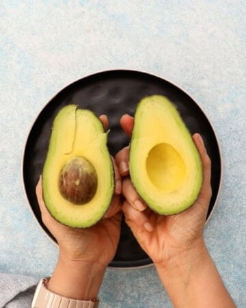 two hands holding an avocado.