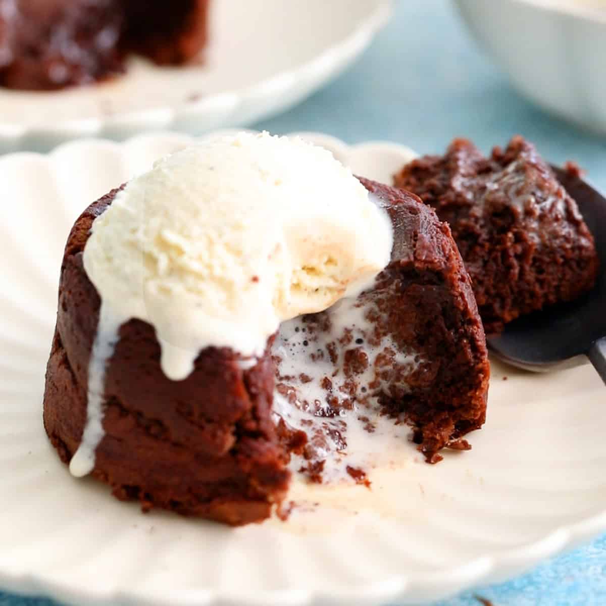 one brown chocolate lava cake topped with white ice cream in a white plate.