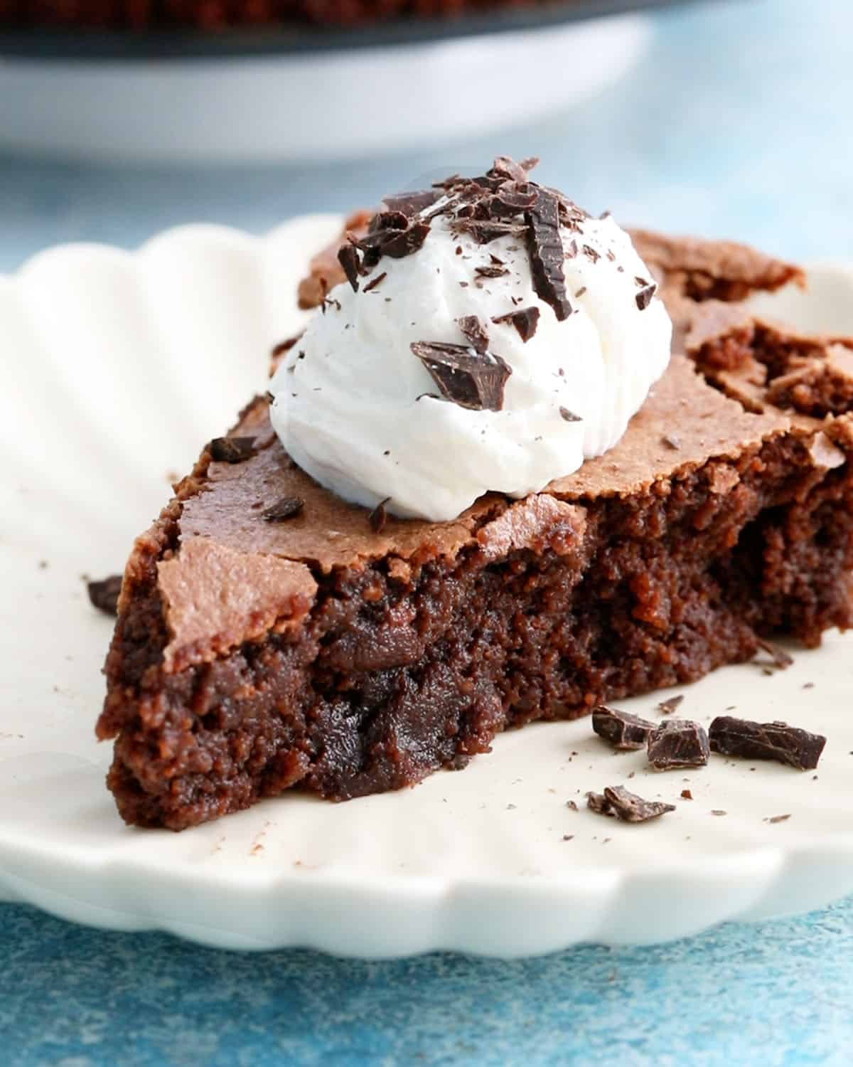 one slice of almond flour chocolate cake with white cream in a white plate.