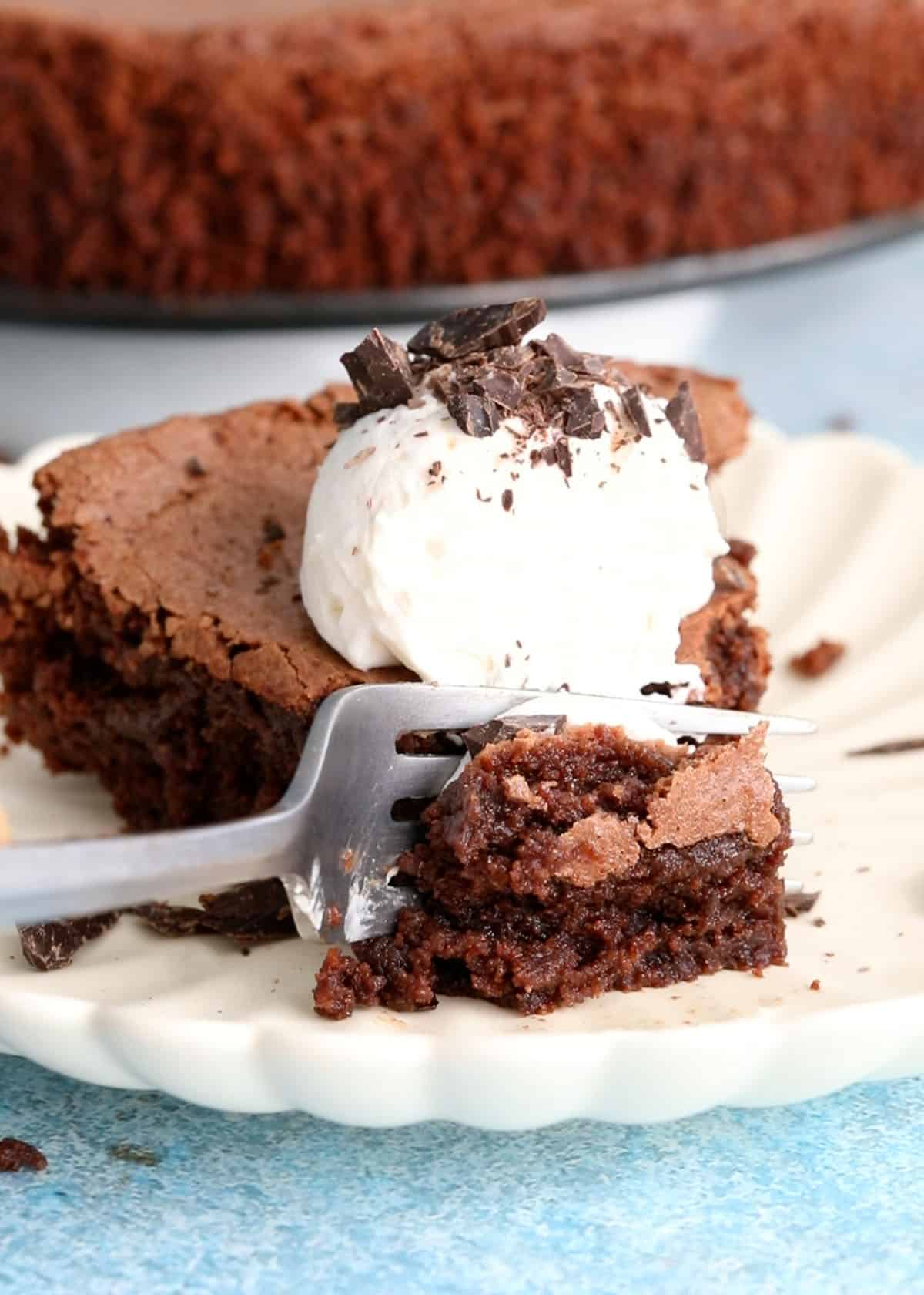 one slice of almond flour chocolate cake with white cream in a white plate.