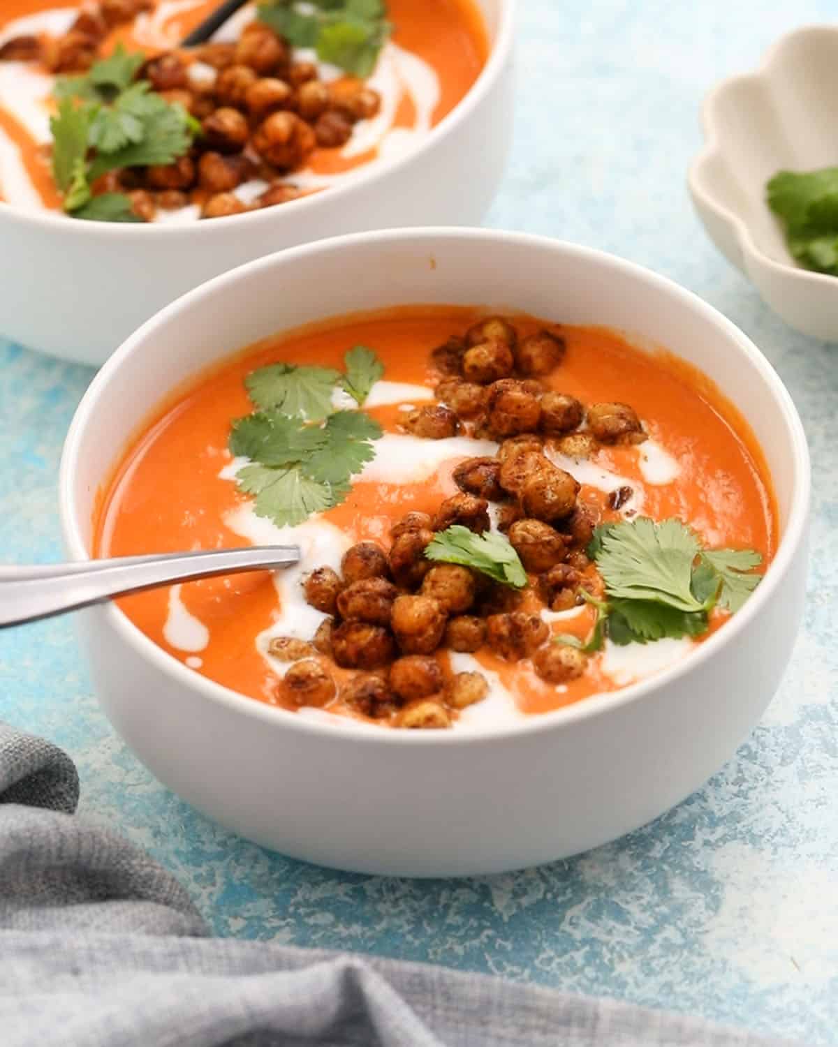 orange colored chickpea soup in a white bowl.