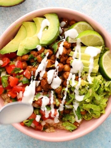 one pink bowl with assembled chickpea burrito bowl.