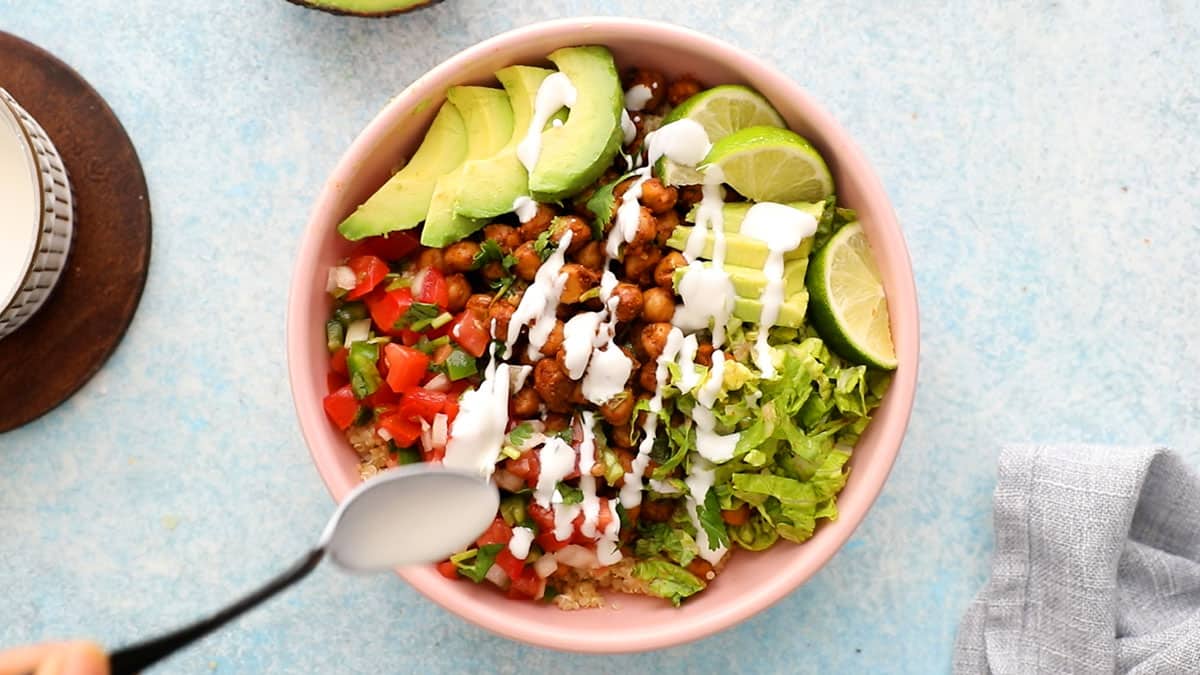 one pink bowl with assembled chickpea burrito bowl.
