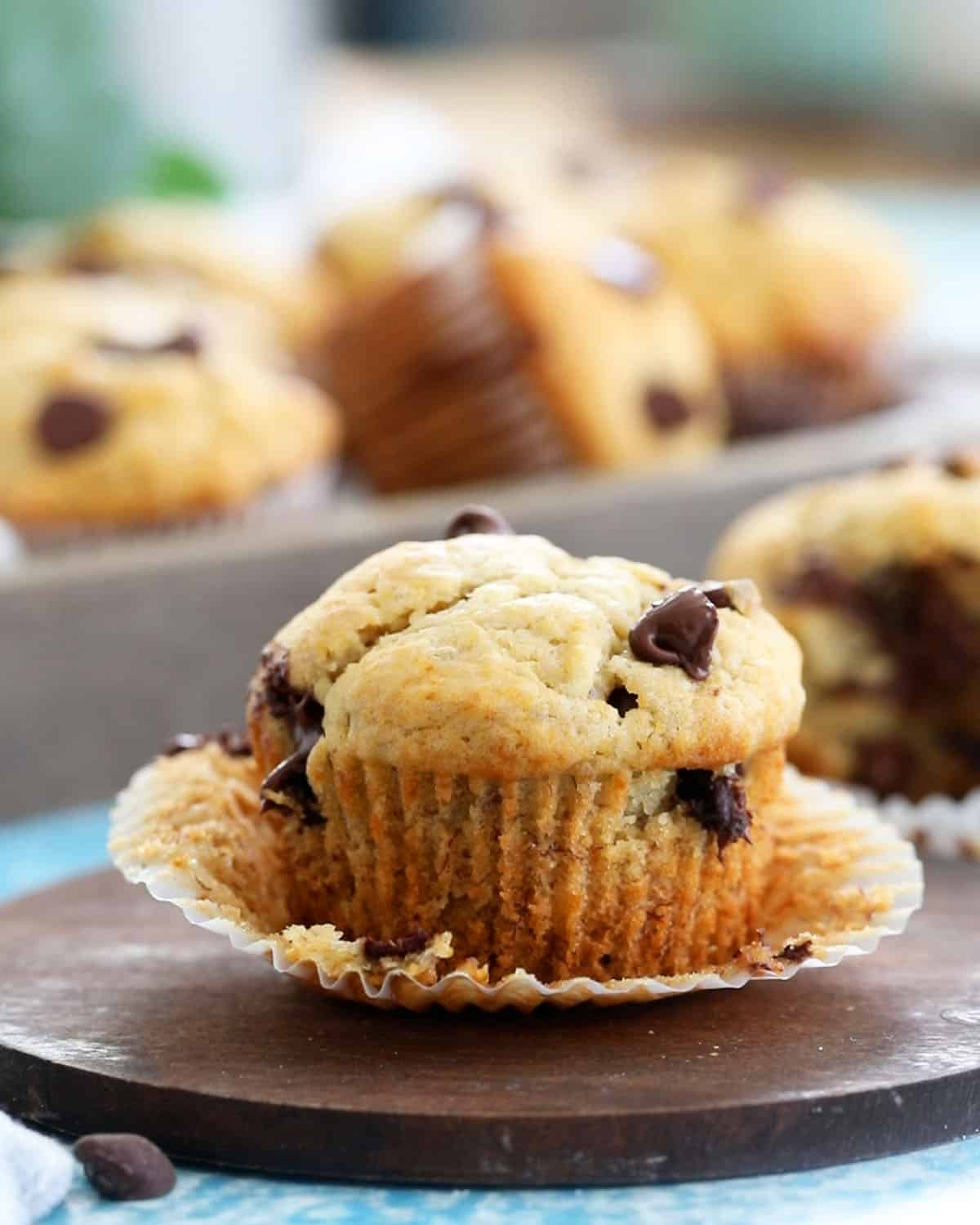 one banana chocolate chip muffin on a wooden board.
