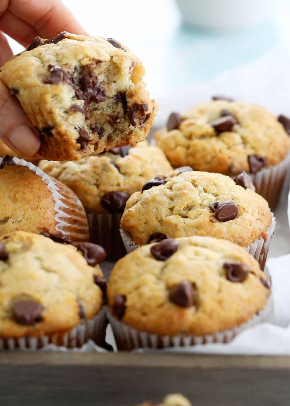 a bunch of brown banana chocolate chip muffins in a wooden board.