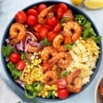 cooked shrimp, pasta and veggies assembled in a large blue bowl.