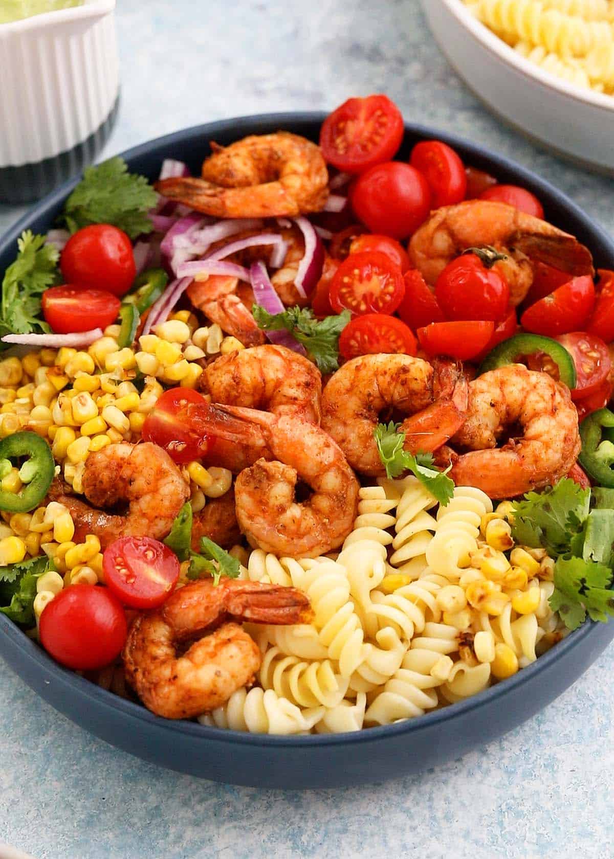 assembled shrimp and pasta salad in a blue bowl.