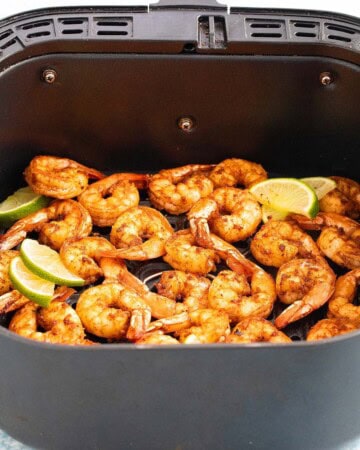 cooked shrimp in an air fryer basket.