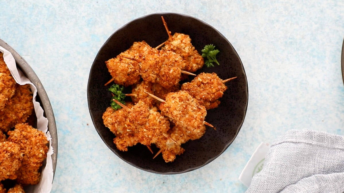 skewered chicken nuggets in a black plate.